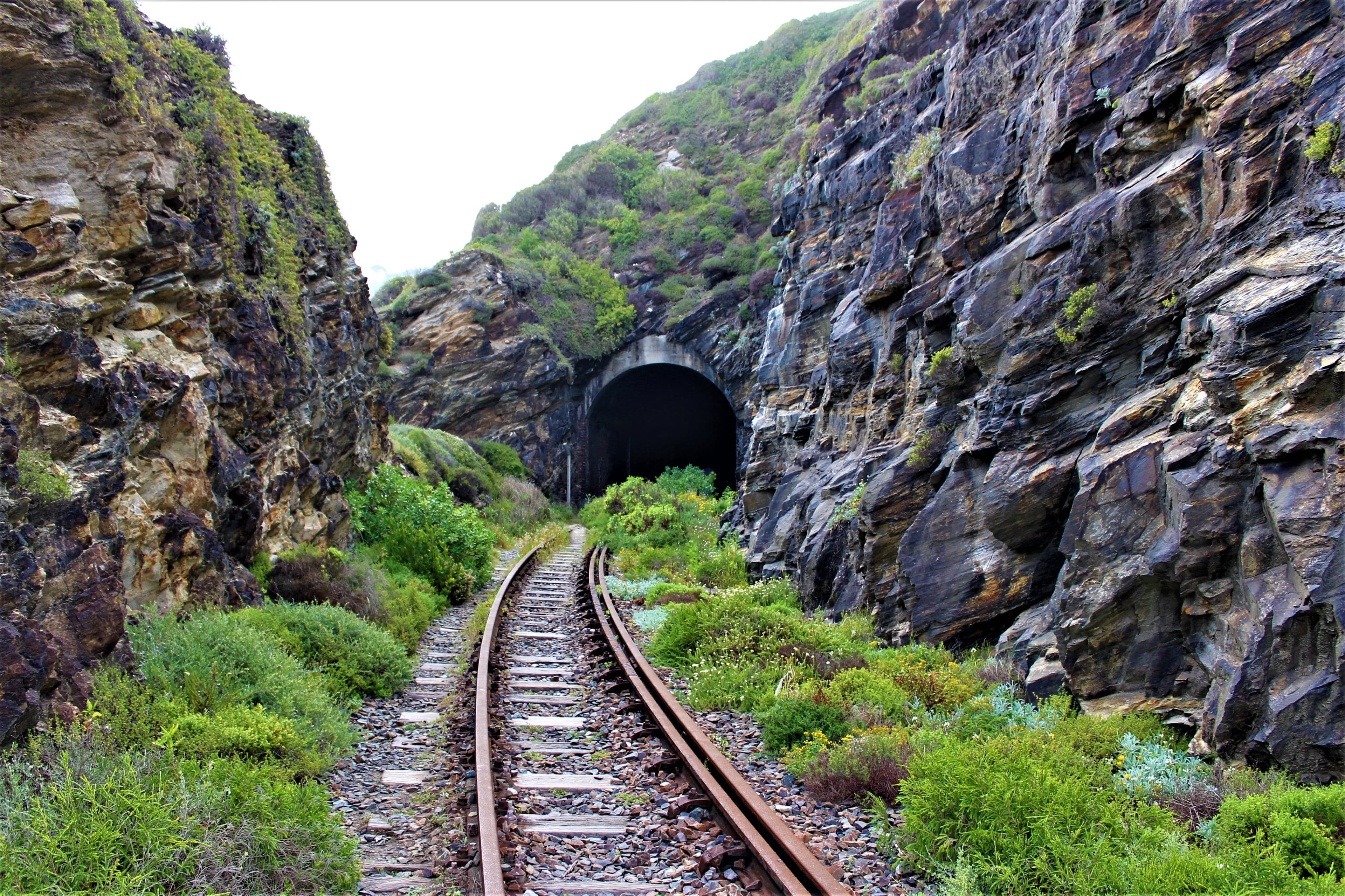 Railway line entering a tunnel through a rocky hillside