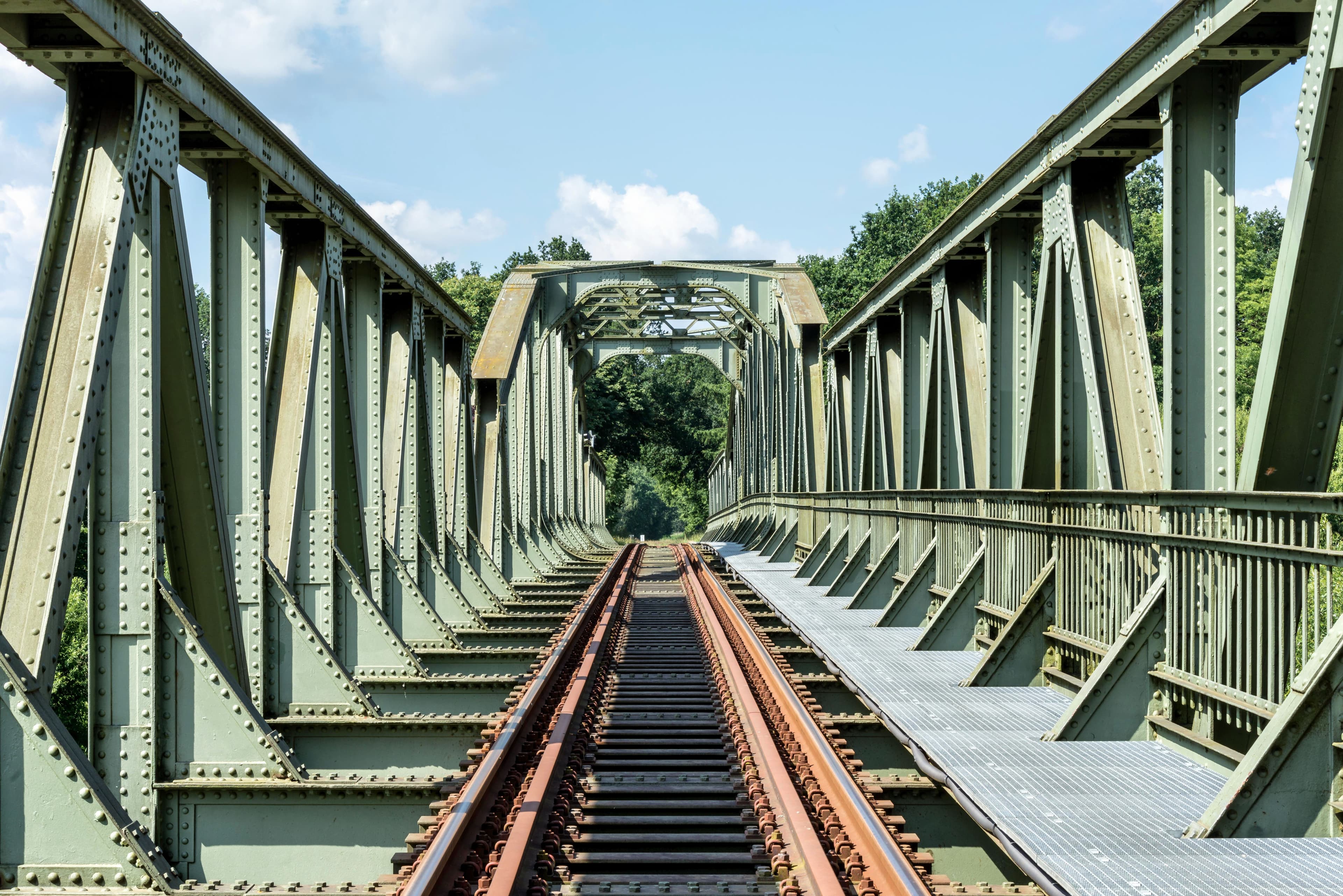 Railway bridge carrying tracks through a green landscape